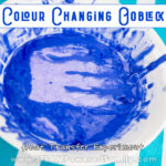 On a teal and white striped background sits a white bowl filled with blue oobleck that has a purple handprint in the centre. Overlay text says Colour Changing Oobleck a Heat Transfer Experiment