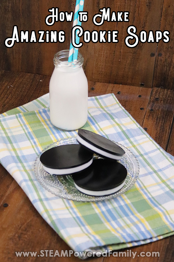 On a wood background is a folded white, blue and light green plaid patterned napkin. On top of the napkin is a glass bottle of milk with blue straws and a plate with soaps that look like cookies with black outer layers and a white middle layer. Overlay text says How to Make Amazing Cookie Soaps
