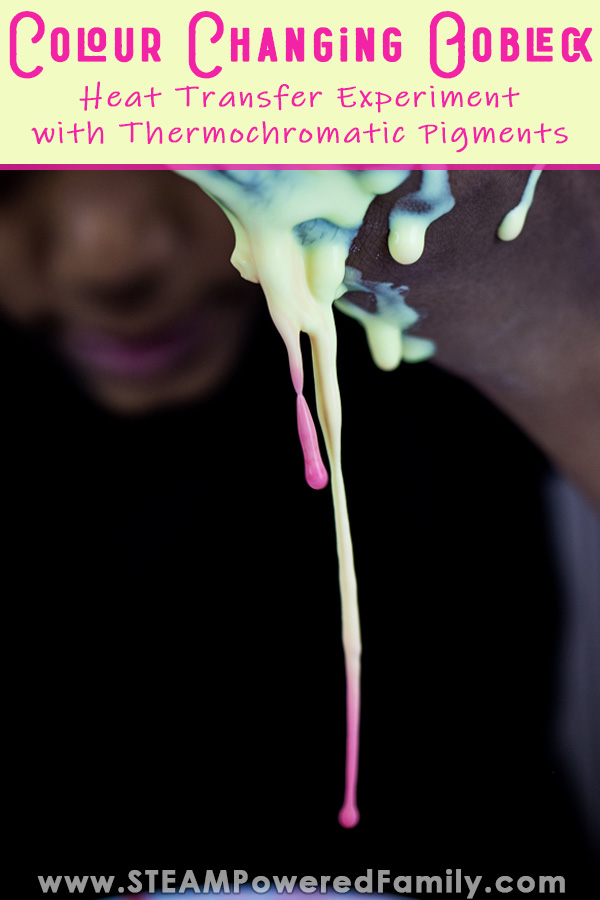 A boy peers with a smile as non-Newtonian Fluid Oobleck drips from his hand, it is yellow near his brown skin and turns pink at the bottom of the drips. Overlay text says Colour Changing Oobleck A Heat Transfer Experiment with Thermochromatic Pigment