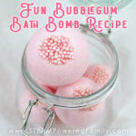 Pink bath bombs with pink bubble shaped pearls set in the ends, are stored in a jar on a white background. Overlay text says Fun Bubble Gum Bath Bomb Recipe