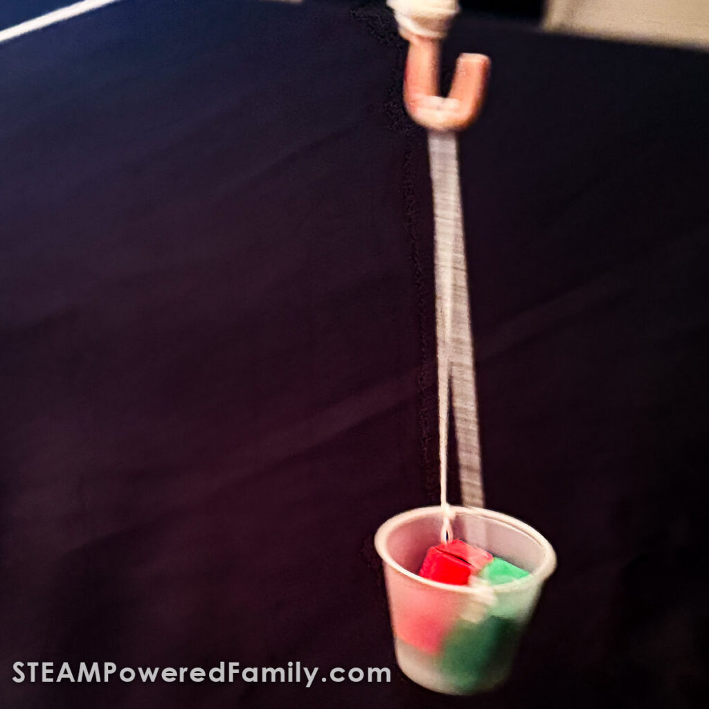 Candy cane zip line carrier moving a small wrapped block down a string.