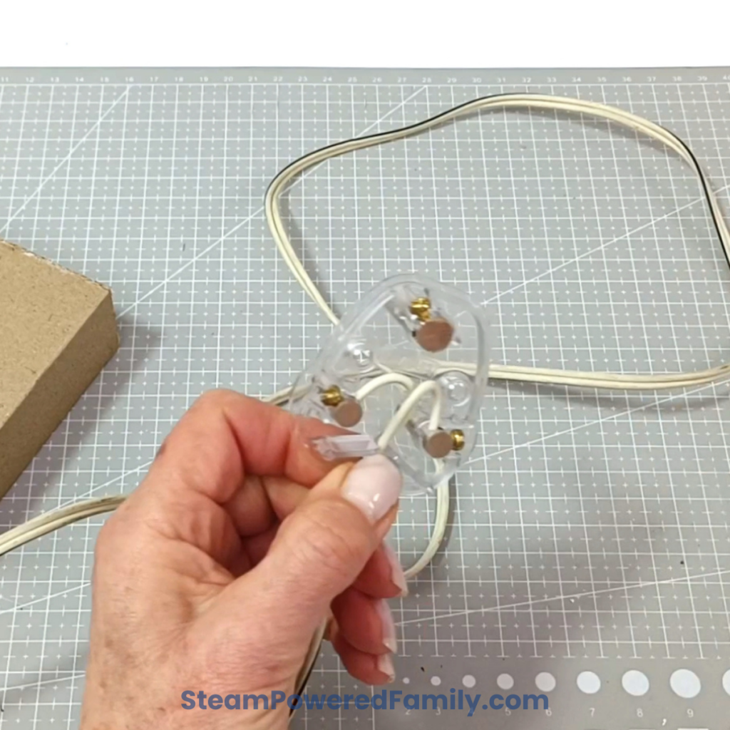 Bare wires installed into the live and neutral positions of an electrical plug for the wired DIY Pringles Can Lamp.