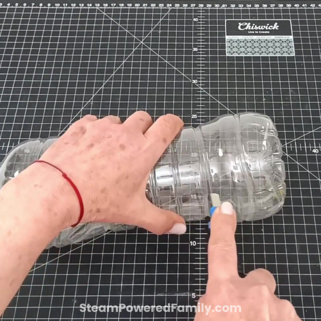 Cutting the bottom third off a plastic bottle to create the catch basin for the water filtration experiment.